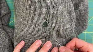 From the front side, insert the needle at least one needle‑length diagonally away from the damage, approximately 2 inches (~51 mm), and come up 1/4 inch (~6 mm) diagonally away from one corner of the damage.