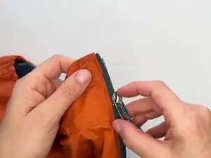 Deslize o cursor do zíper danificado para cima, separando-o da fita do zíper.