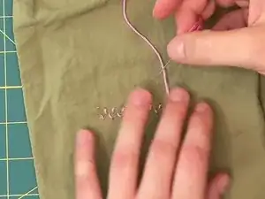 Once you push the needle through the final puncture point, leave the needle on the back side of the fabric.