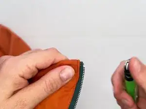 Com um isqueiro, chamusque a fita do zíper desfiada ou danificada.