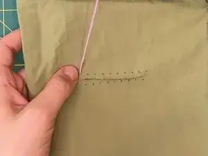 Insert the needle back into the fabric through the marked puncture point next to the thread.
