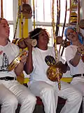 Praticantes de capoeira tocando berimbau