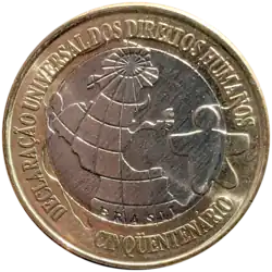 Moeda de um real comemorativa dos 50 anos da Declaração Universal dos Direitos Humanos. Possui um núcleo prateado com figura humana, representativa do logomarca oficial do evento, e o globo terrestre. Ao redor, possui um anel dourado com as inscrições "Declaracao Universal dos Direitos Humanos", "Cinquentenario" e "Brasil"