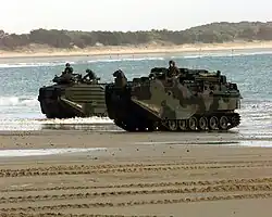 Fuzileiros em treinamento desembarcando com seus veículos blindados em uma praia.