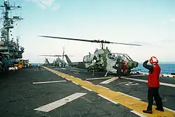 Um helicóptero AH-1W Cobra decolando do USS Tripoli, 1992