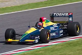 Aguri Suzuki e o Lola LC90 pilotado por ele e Éric Bernard na temporada de 1990, durante uma apresentação em 2012.