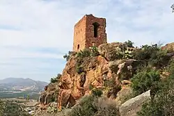 Foto de torre de pedra arruinada, com dois pisos de altura.
