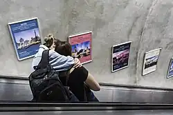 Casal desce escada rolante.