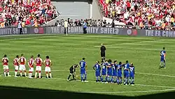 Jogadores de ambos Arsenal e Chelsea no círculo central de um campo de futebol.