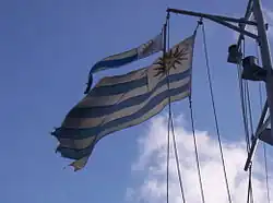 Flâmula do Uruguai arvorada, em conjunto com a respetiva bandeira nacional, no mastro do navio-balizador ROU Sirius.