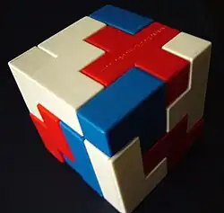 Imagem de um cubo formado por blocos de peças brancas, vermelhas e azuis