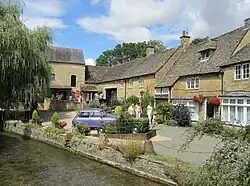 De cima para baixo: ponte sobre o rio Windrush; Museu do Motor; Memorial de Guerra e Village Green; pinguins em Birdland; Aldeia ModeloModel Village