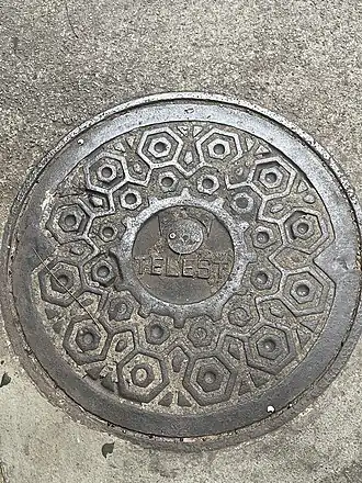 Bueiro com a logotipo da empresa Telest em uma rua na cidade de Vitória