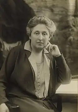 A posed black and white photograph of a woman seated at a desk