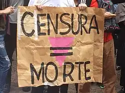 cartaz confeccionado em papel a metro, escrito a mão com os dizeres Censura = Morte, ilustrado por um triângulo rosa, símbolo utilizado pelos nazistas para identificar homossexuais nos campos de concentração.