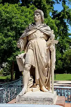 Um homem de meia-idade que usa uma cota de malha coberta por um casaco e segura uma espada