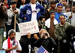 Uma faixa com a inscrição "Chicano Power!" segurada por membros da M.E.Ch.A. na CSULA em meio a uma multidão (2006).