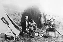 Een foto van Louis Wessels (links) met twee andere mannen voor een tent.