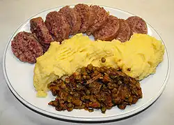 Boiled cotechino Modena (top) served with polenta and lentils (bottom)