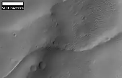 Imagem da foto anterior de um tergo curvo que pode se tratar de um antigo canal que se inverteu. Imagem obtida pela HiRISE sob o programa HiWish.