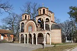 Igreja branca e laranja com grama ao redor.