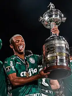 Um homem segurando uma taça e sorrindo
