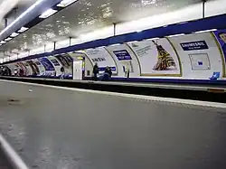 Vista geral da plataforma em direção a Créteil da linha 8. Aqui, novamente, o estilo "Andreu-Motte" é visível com banqueta, assento e faixa de iluminação em azul.