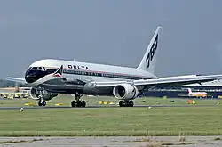 Side view of twin-engine jet touching down on runway, with deployed flaps and thrust reversers