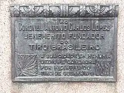 Detalhe da inscrição do monumento em homenagem ao Coronel Antonio Carlos Lopes. Inscrição: "Ao Coronel Antonio Carlos Lopes benemérito fundador do tiro brasileiro. A sua cidade em memória dedica e consagra por iniciativa do tiro de guerra nº 1. 19-9-1937