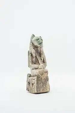 Representação de uma deusa com corpo de mulher e cabeça de leoa sentada em um trono cujas laterais estão figuras incisas do deus serpente Nehbkau. Com as duas mãos a deusa, provavelmente, segurava um sistro. Em sua nuca, sobre o toucado tripartite, estava o anel de sustentação. Fragmentada abaixo dos joelhos e na parte inferior do trono. Item da Coleção Egípcia da Casa Museu Eva Klabin.Materiais: Faiança Egípcia. Dimensões: Altura: 4,5 cm; Largura: 1,8 cm; Profundidade: 2,7 cm. Origem: Egito.