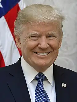 Retrato oficial de Donald Trump usando um terno azul marinho e sorrindo em frente à bandeira dos Estados Unidos.