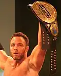 Eli Drake com uma versão modificada do quarto design de cinturão, que adicionou uma placa "Impact Wrestling" ao cinturão para cobrir o logo da Global Force Wrestling após o breve uso desse nome pela empresa.