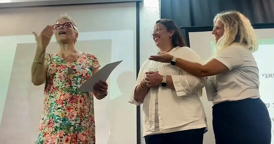 Eti Schwerzberg (centro), presidente da Acha, e Mirit Eliyahu (direita), membro do conselho da Acha, entregam um certificado de agradecimento a Moshe Shem Tov para Ofra (esquerda), sua filha, Casa Helen Keller, julho de 2024.