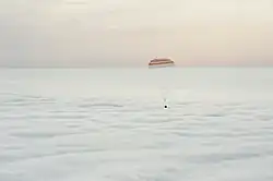 A cápsula desce sobre um tapete de nuvens para o pouso no Casaquistão.
