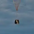 A cápsula suspensa pelo paraquedas a caminho do solo.