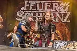 Um grupo de músicos no palco usando vestimentas da Europa medieval