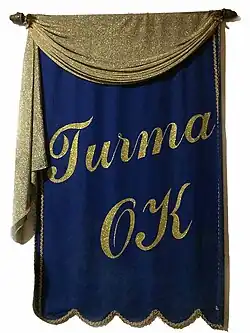 Flâmula original do clube social Turma OK, confeccionada em veludo com letras em detalhes ouro