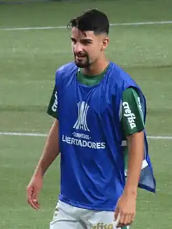 Um homem em um campo de futebol, vestindo uniforme, e com um colete