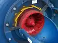 Turbina Francis com dutos (em azul) parcialmente removidos, mostrando o rotor (vermelho) e as pás estáticas (amarelo) ajustadas para fluxo mínimo.