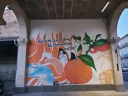 The Clementine Mural painting in Puisserguier France, representing Father Abram, founder of the Algerian Misserghin orphanage where the 1st citrus clementina was selected by brother Clement, a map of the different locations mentionned, and the citrus flowers, whole smooth fruit and some of its easy to peel separated sections.