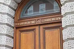 Entrada da Sociedade Geológica de Londres com porta de madeira e letreiro dourado.