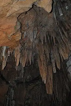Formação de estalactites no teto da caverna, assemelhando a espinhos orientados para o chão,