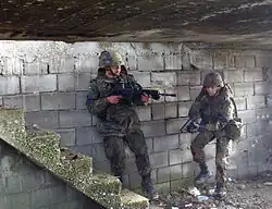 Soldados da Bundeswehr usando um fuzil G36 e uma HK P8 em um exercício militar.