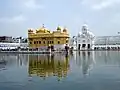 Harmandir Sahib (Templo Dourado) com a Torre do Relógio ao fundo.