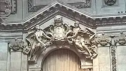 Armas de estilo neoclássico, com a esfera armilar contendo a sigla "RP" coroando o escudo (em substituição da coroa real original). Grupo escultórico de Teixeira Lopes na sala das sessões da atual Assembleia da República, 1903