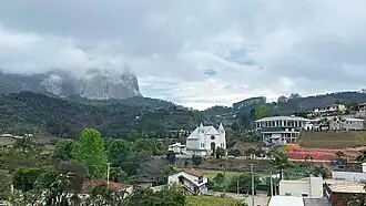 Igreja Matriz de Nossa Senhora de Fátima em Aracê com a Pedra Azul ao fundo à esquerda, encoberta por um nevoeiro.