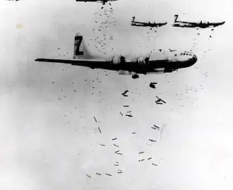 Fotografia em preto e brancoBlack and white de três aeronaves multimotores voando em formação enquanto soltavam um grande número de bombas