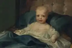 Retrato de um bebé com um vestido branco, num leito com cobertores e almofada de seda azul.