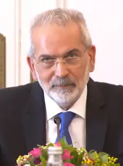 loannis Sarmas de terno e óculos olhando diretamente para a câmera