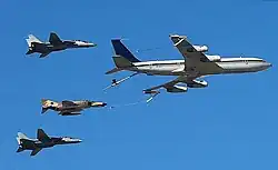 Um avião cargueiro Boeing 707 da força aérea do Irã voando com dois F-14 e um F-4.